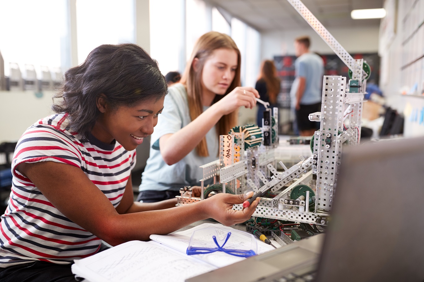 Two female college students building machine in science and robotics