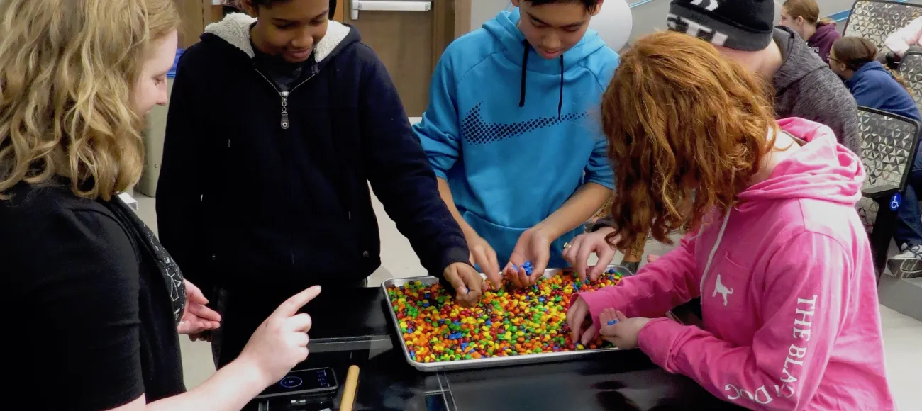 Student participants implement an M&M model of biological evolution as Siera gives pointers