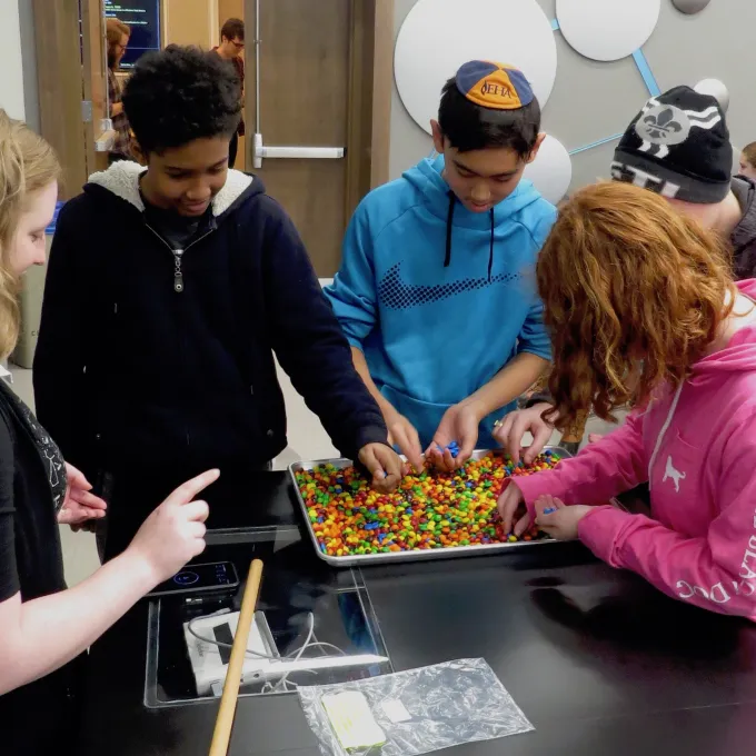 Student participants implement an M&M model of biological evolution as Siera gives pointers